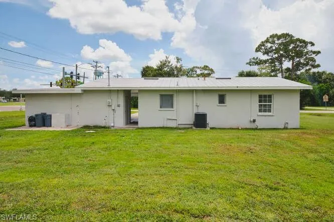 Back of house with a lawn and stucco siding