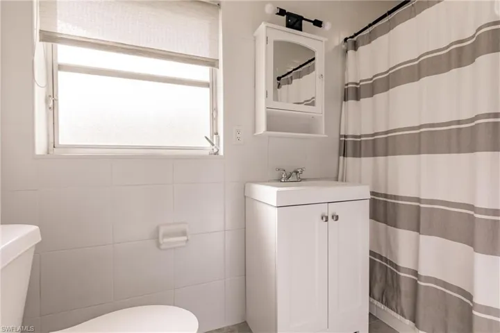 Full bathroom with curtained shower, vanity, and tile walls