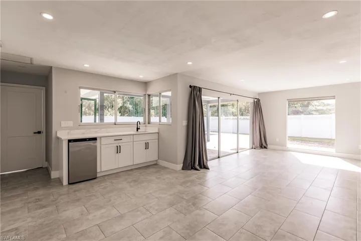 Kitchen featuring white cabinetry, dishwasher, recessed lighting, light tile patterned flooring, and open floor plan