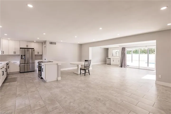 Kitchen featuring appliances with stainless steel finishes, white cabinetry, open floor plan, a center island, and recessed lighting