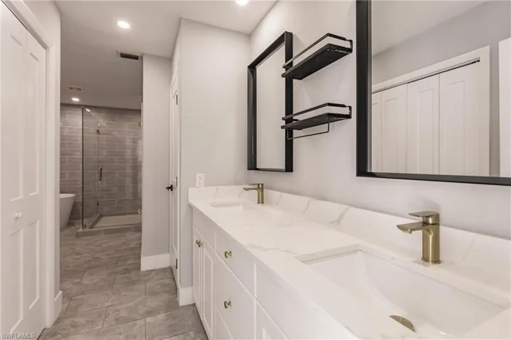 Full bathroom with a stall shower, double vanity, recessed lighting, light tile patterned floors, and a soaking tub