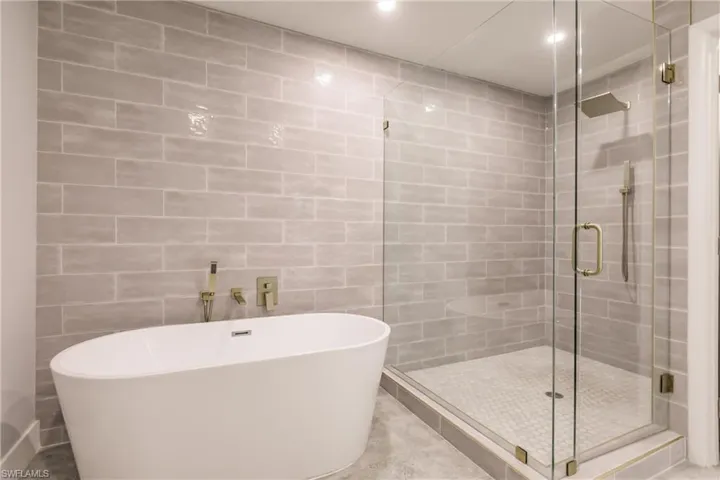 Full bathroom featuring a freestanding tub, a stall shower, and tile walls