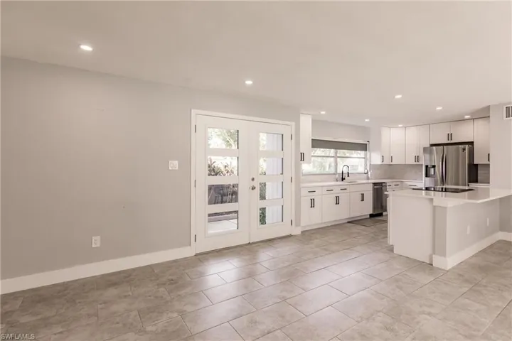 Kitchen with white cabinets, recessed lighting, appliances with stainless steel finishes, french doors, and a breakfast bar