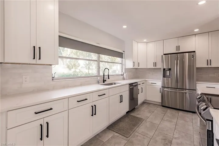Kitchen featuring appliances with stainless steel finishes, white cabinetry, recessed lighting, light stone counters, and light tile patterned floors