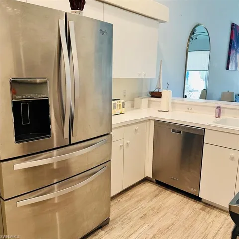 Kitchen with stainless steel appliances, light wood-type flooring, light countertops, and white cabinetry