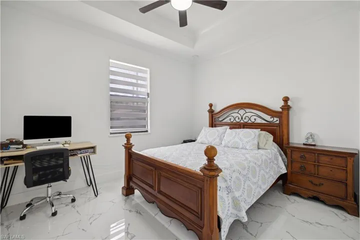 Tiled bedroom featuring ceiling fan and a tray ceiling