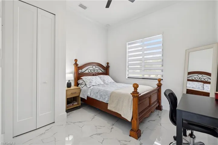 Tiled bedroom with a closet, ceiling fan, and crown molding