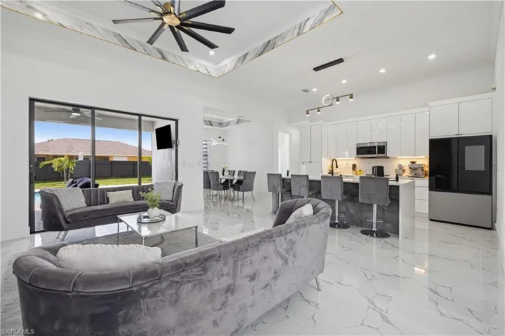 Tiled living room featuring sink, ceiling fan, and crown molding