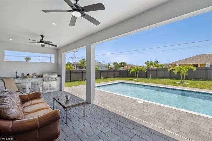 View of pool featuring a patio, an outdoor kitchen, grilling area, ceiling fan, and a yard