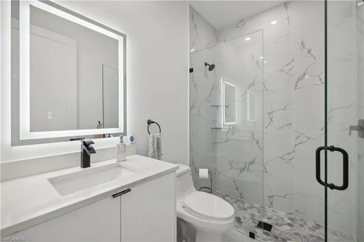 Bathroom featuring vanity, an enclosed shower, and toilet