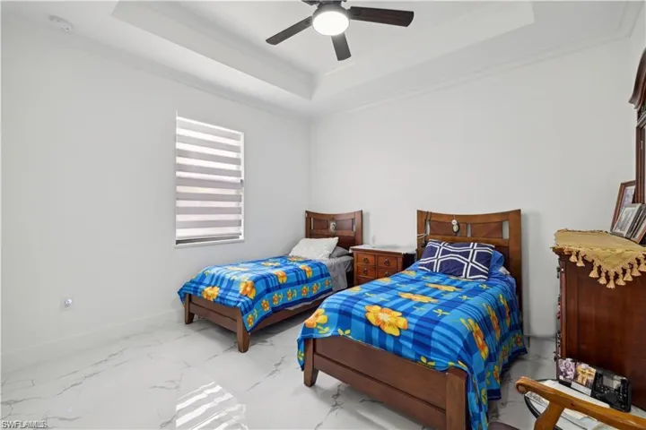 Bedroom with crown molding, tile patterned flooring, a raised ceiling, and ceiling fan