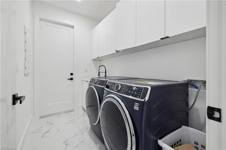 Laundry area with cabinets, washer and dryer, and light tile patterned floors