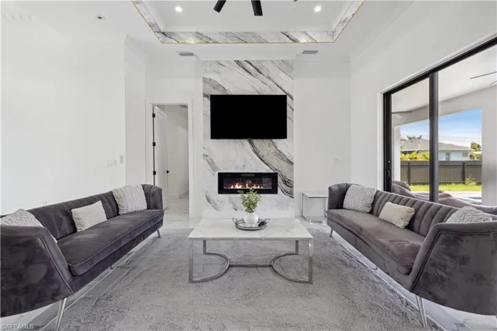 Living room with ornamental molding, a high end fireplace, and ceiling fan