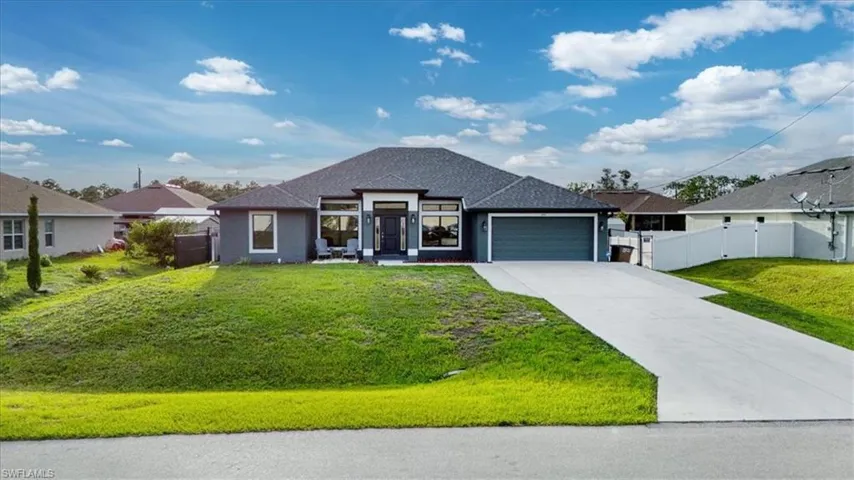 Contemporary stucco exterior with a gray palette, featuring a dark gray roof, an attached garage with a matching door, a concrete driveway, and a manicured front lawn