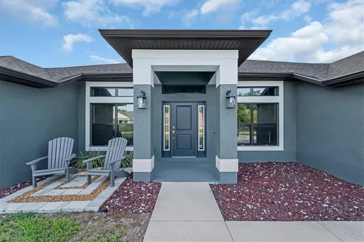 Contemporary single-story exterior with a covered entry, featuring textured stucco siding, a dark asphalt shingle roof, and a prominent front door with a vertical window insert