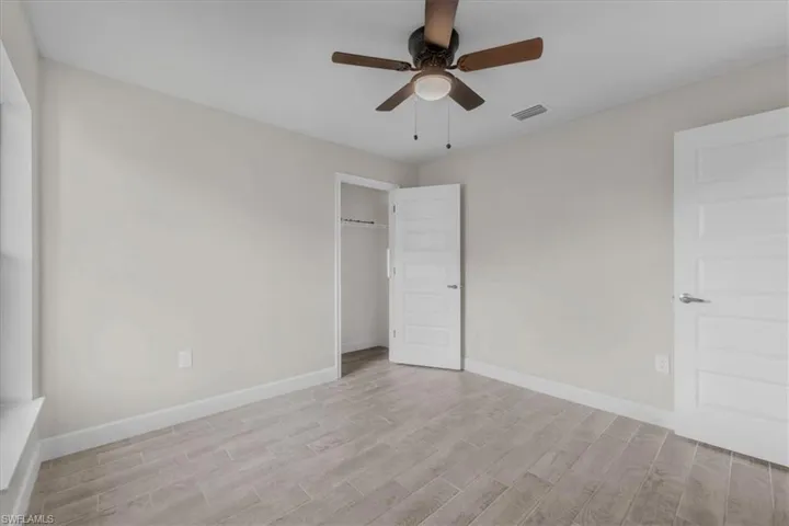 Room featuring wood-look tile flooring, light-toned walls, a modern ceiling fan, and white five-panel interior doors
