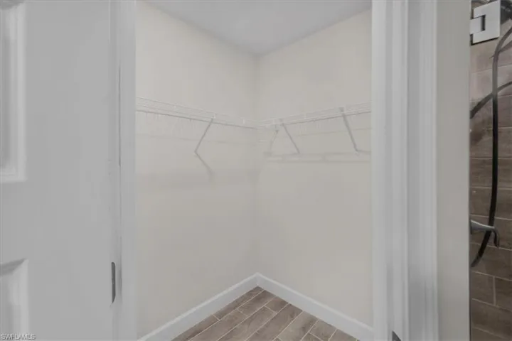 Walk-in closet featuring wood-finish tile flooring, white baseboards, and white wire shelving
