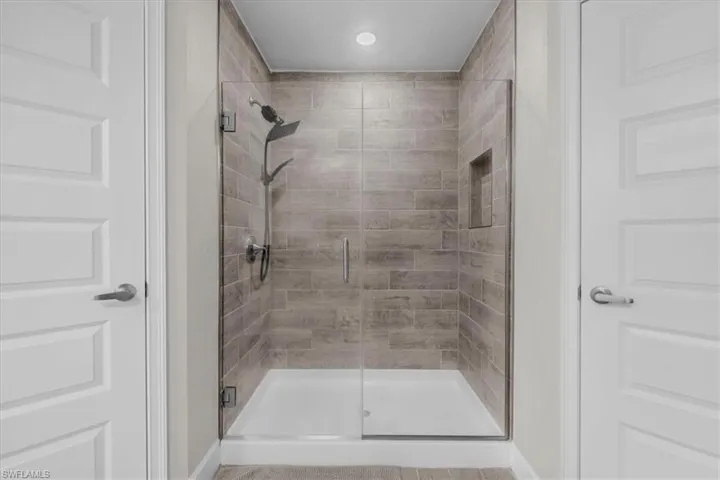 Walk-in shower with clear glass enclosure and a white base