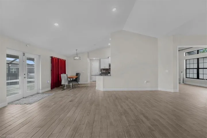 Spacious open concept interior featuring wood-finish flooring, vaulted ceilings, and recessed lighting