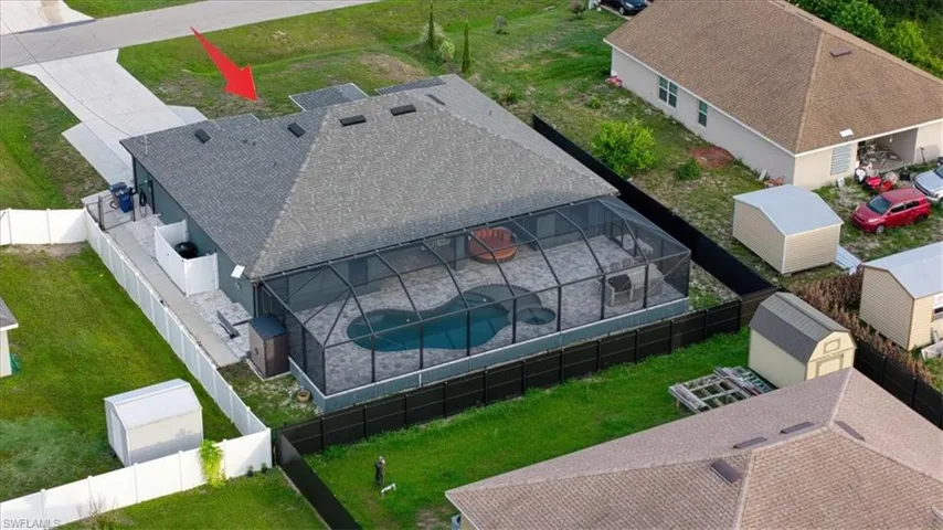 Rear exterior featuring a screened-in pool enclosure, an irregular-shaped pool with an integrated spa, and a concrete patio