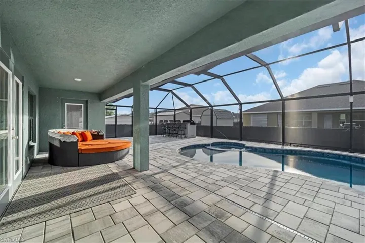 Screened-in outdoor living space with a concrete patio, integrated swimming pool, and raised spa