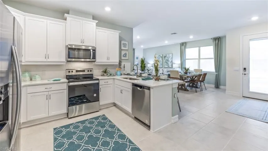 Contemporary kitchen with white cabinetry, stainless steel appliances, and light-toned tile flooring