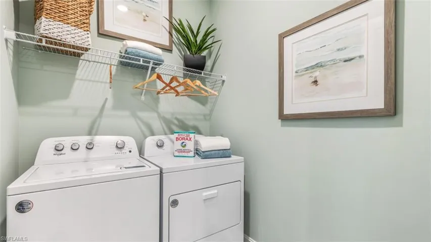 Laundry area with white appliances and wall-mounted wire shelving
