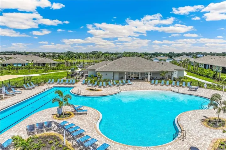 Expansive pool area featuring a large freeform pool, a lap pool, a spacious paver deck, and surrounding lounge seating