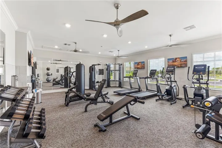 Fitness center featuring multiple ceiling fans, recessed lighting, expansive windows, and wall-mounted mirrors
