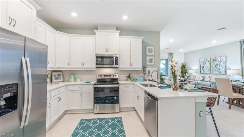 Well-appointed kitchen featuring white cabinetry, stainless steel appliances, and light-colored countertops