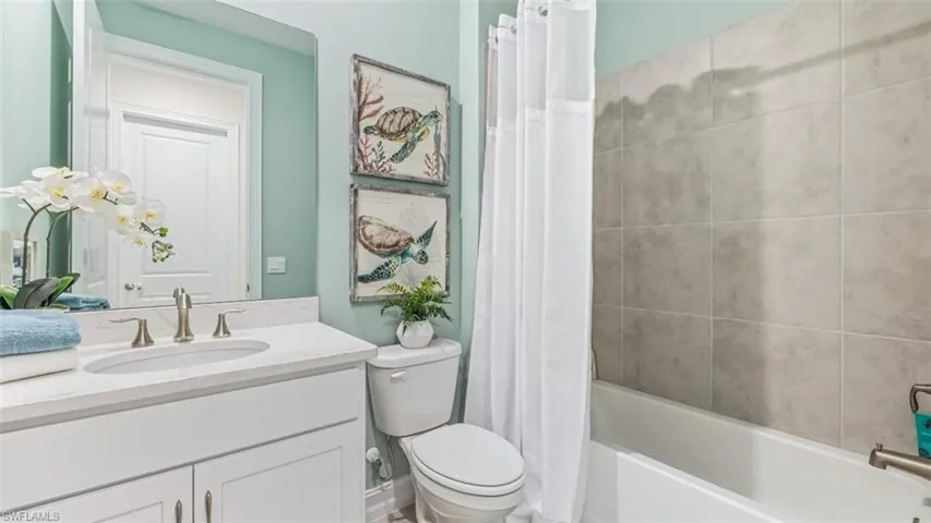 White vanity with a single basin sink, brushed nickel faucet, and a large wall mirror