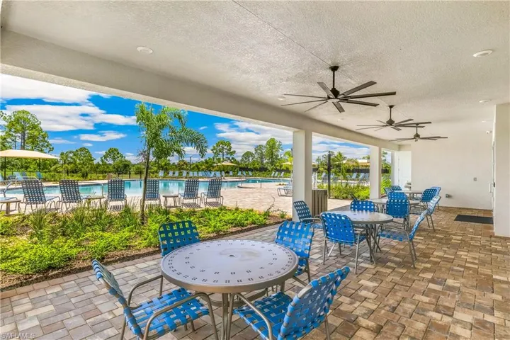 Covered outdoor patio with multiple ceiling fans, paver flooring, and direct access to a swimming pool