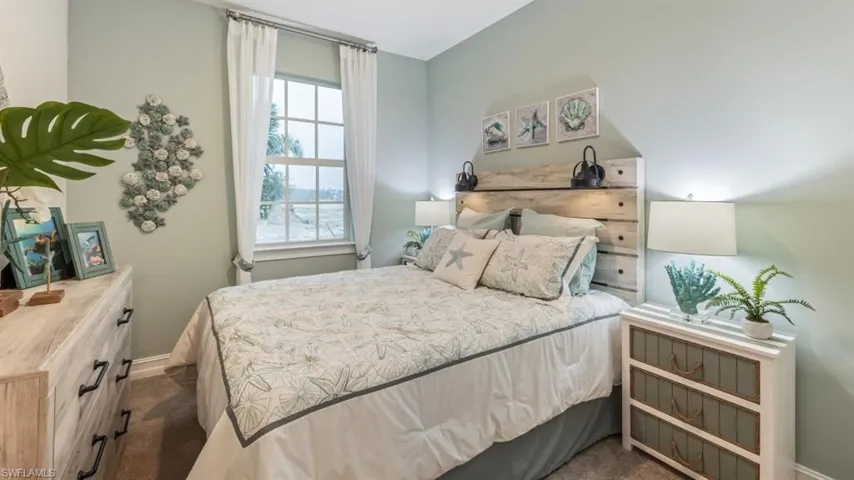 Recessed window with white curtains, wood-finish flooring, light-toned walls, built-in wooden headboard, and attached wall sconces