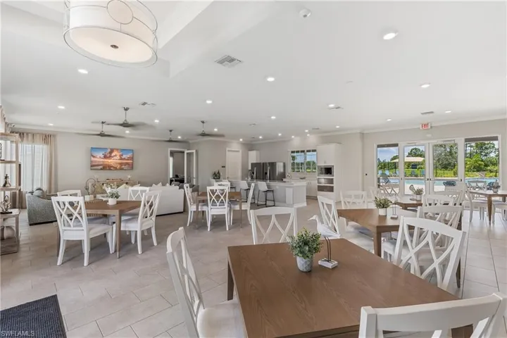 Spacious open-concept interior featuring light-toned tile flooring, recessed lighting, ceiling fans, and a contemporary kitchen with white cabinetry