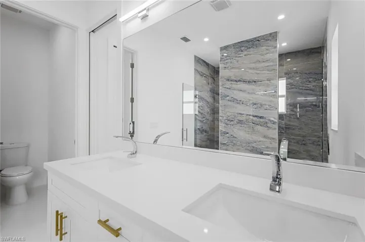 Bathroom with toilet, an enclosed shower, and vanity