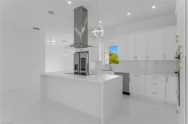 Kitchen featuring white cabinets, appliances with stainless steel finishes, island exhaust hood, and pendant lighting