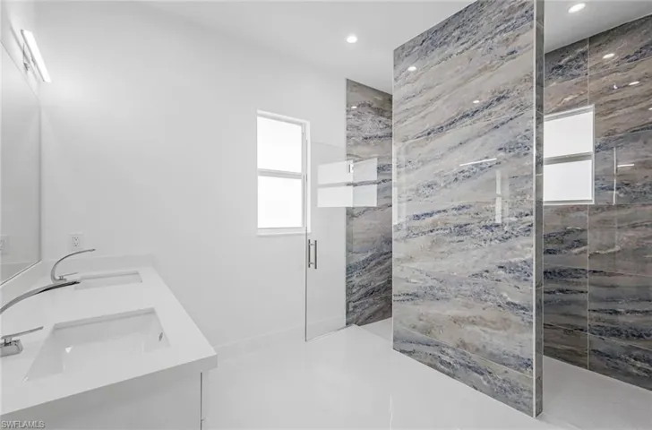 Bathroom featuring tiled shower and vanity