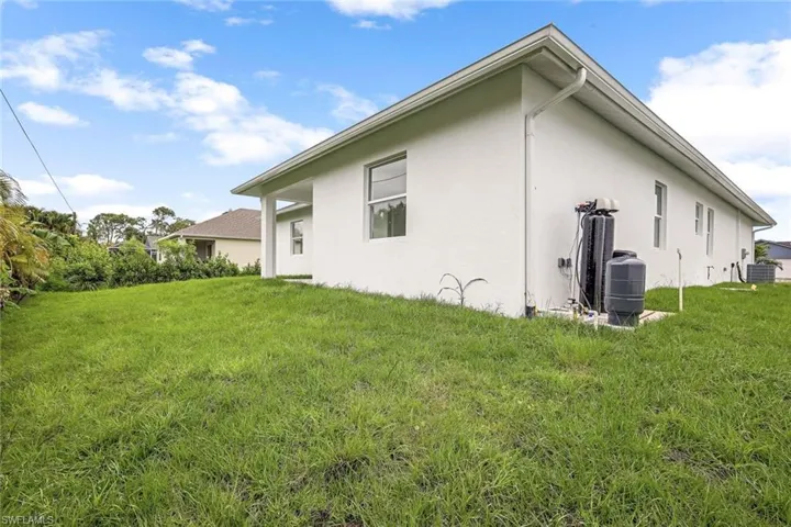Back of property featuring central AC unit and a lawn