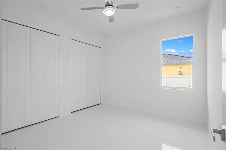 Unfurnished bedroom featuring ceiling fan, multiple closets, and tile patterned flooring