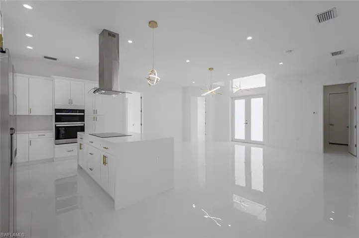 Kitchen with a kitchen island, white cabinets, double oven, island range hood, and black electric cooktop