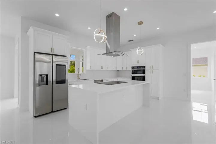 Kitchen with a center island, black appliances, sink, island exhaust hood, and hanging light fixtures