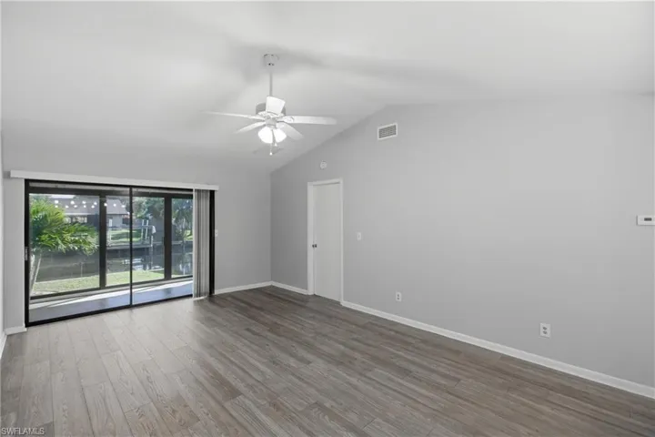 Empty room with light wood-style floors, lofted ceiling, and a ceiling fan
