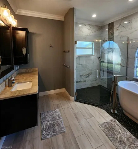 Bathroom featuring vanity, independent shower and bath, and crown molding