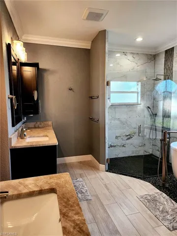 Bathroom featuring shower with separate bathtub, vanity, and crown molding