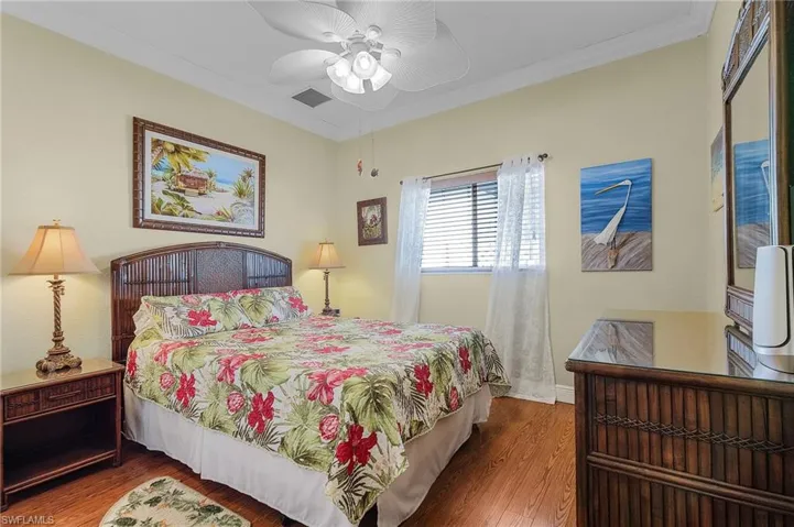 Bedroom featuring ceiling fan, wood-type flooring, and ornamental molding
