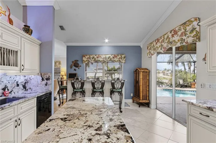Kitchen with light stone countertops, white cabinets, crown molding, dishwasher, and light tile patterned flooring