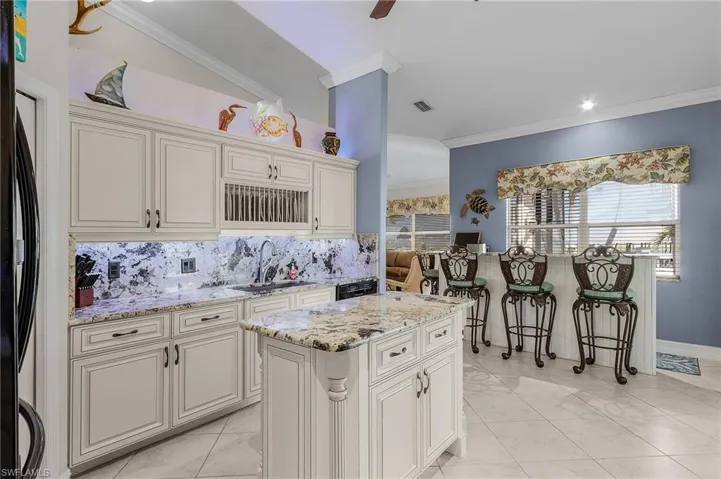 Kitchen featuring tasteful backsplash, a kitchen island, ornamental molding, and sink
