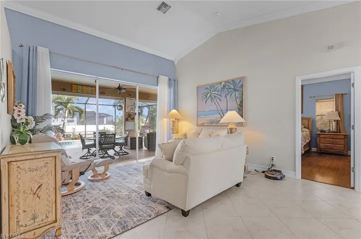 Living room with lofted ceiling, crown molding, and light tile patterned floors