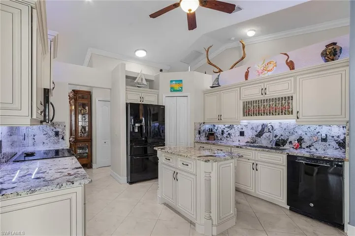 Kitchen featuring ceiling fan, a center island, tasteful backsplash, vaulted ceiling, and black appliances