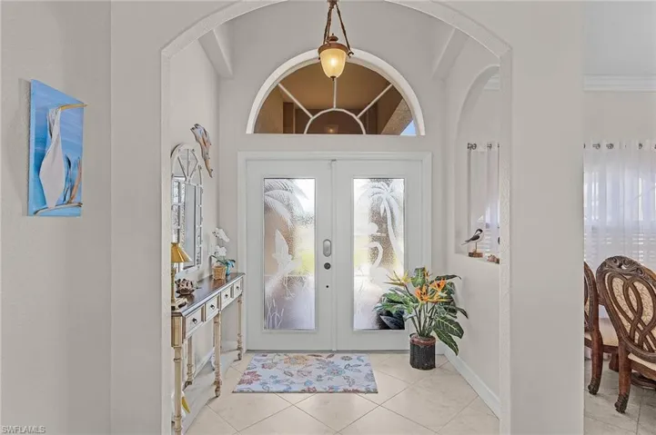Foyer featuring light tile patterned floors, crown molding, and french doors